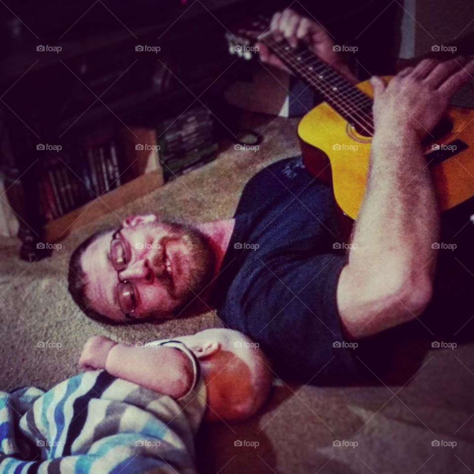 father plays a song on the guitar for his infant son