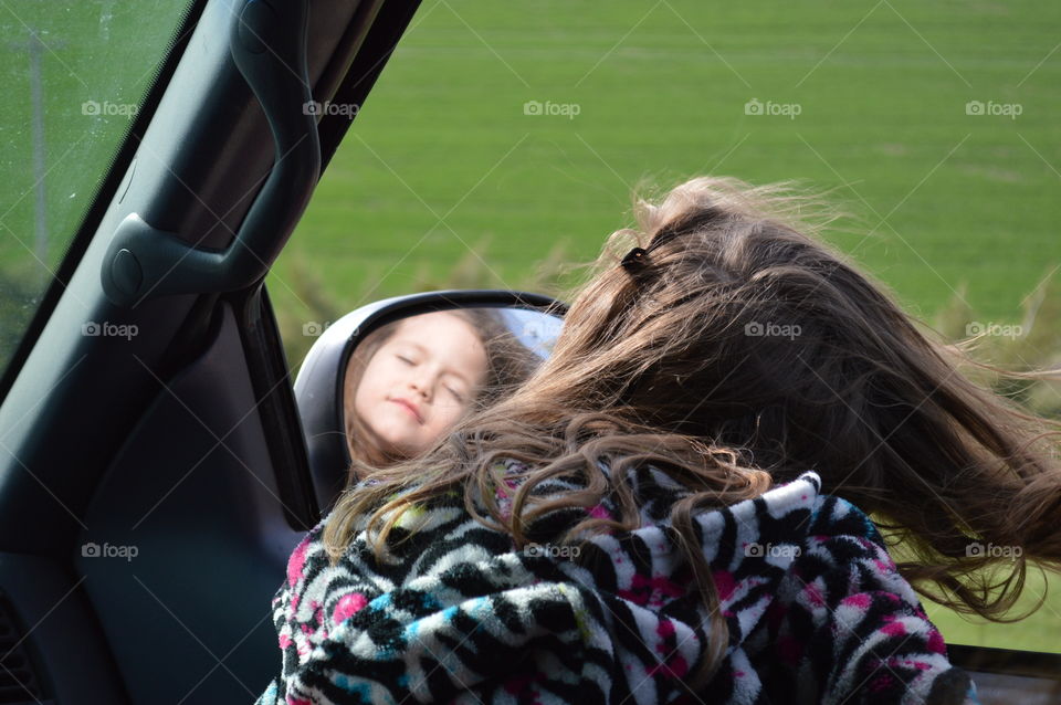 Reflection of little girl face in car mirror