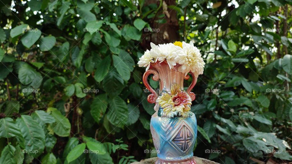 Beautiful white flowers in a colourful flowerpot with a flower sculpture, Flowers in a vase, colourful vase, white flowers in a vase