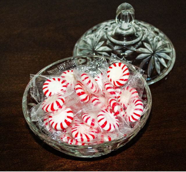 A crystal bowl of cellephone wrapped red and white striped peppermint candies. 