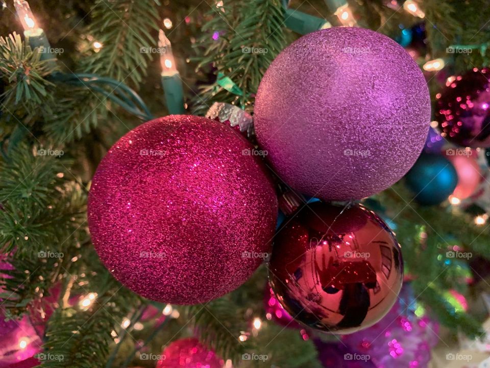 Holiday ornaments glistening in warm Christmas lights.