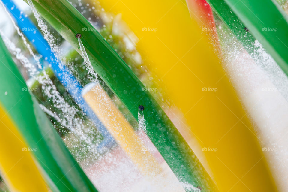 Colorful water fountain in the park with stream going via piles and through the holes