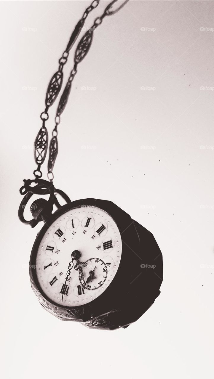 Sepia close-up shot on a vintage pocket watch laid on a mirror