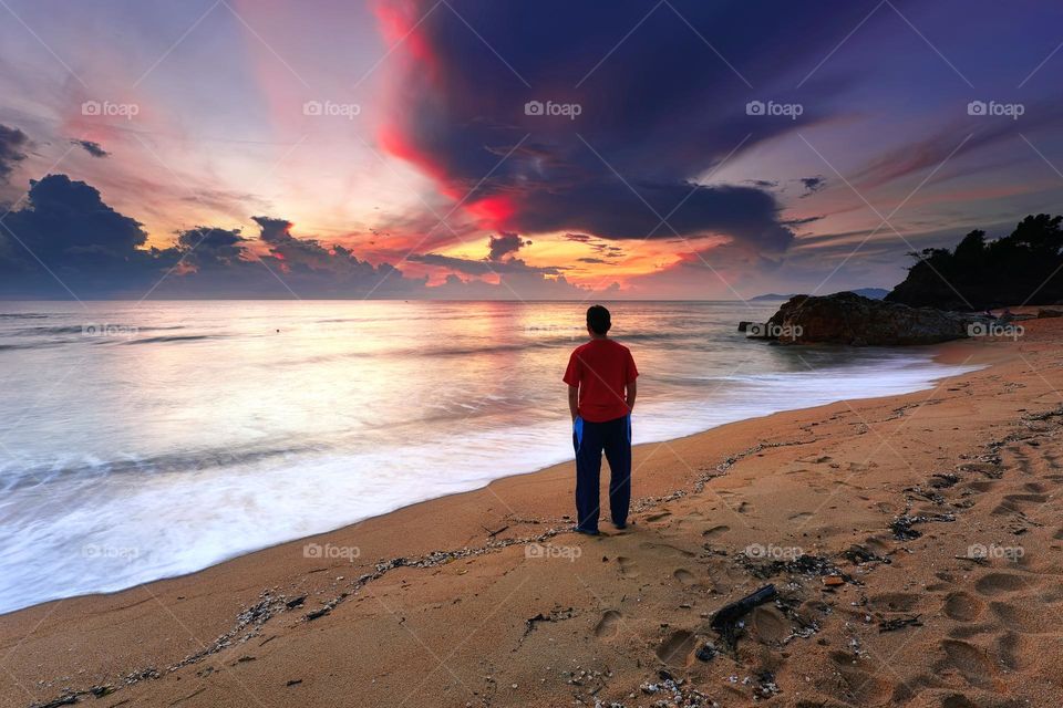 Man standing over the beach at sunrise