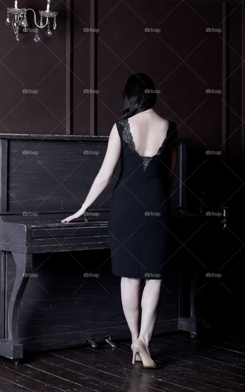 Woman at the piano, in a black dress with an open back