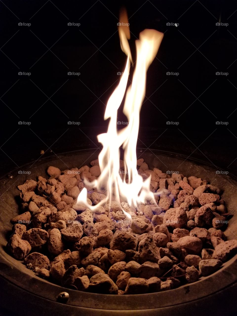 a small fire over a bed of coals at night by a lake.