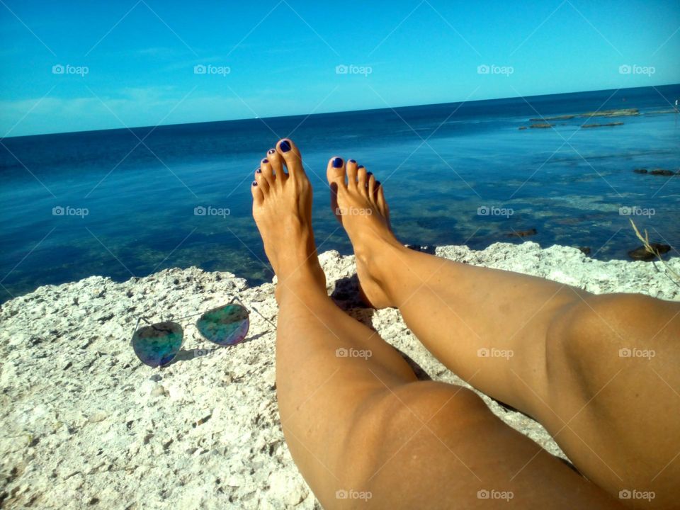 female legs barefoot relaxing on a sea stone summer vacation