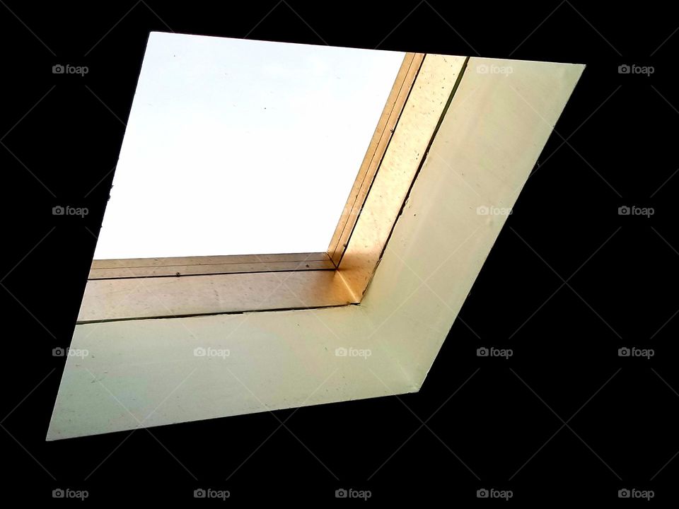 Bronze metal window frame in a skylight, within a darkened room.