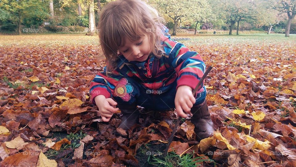 child plating with leaves in fall