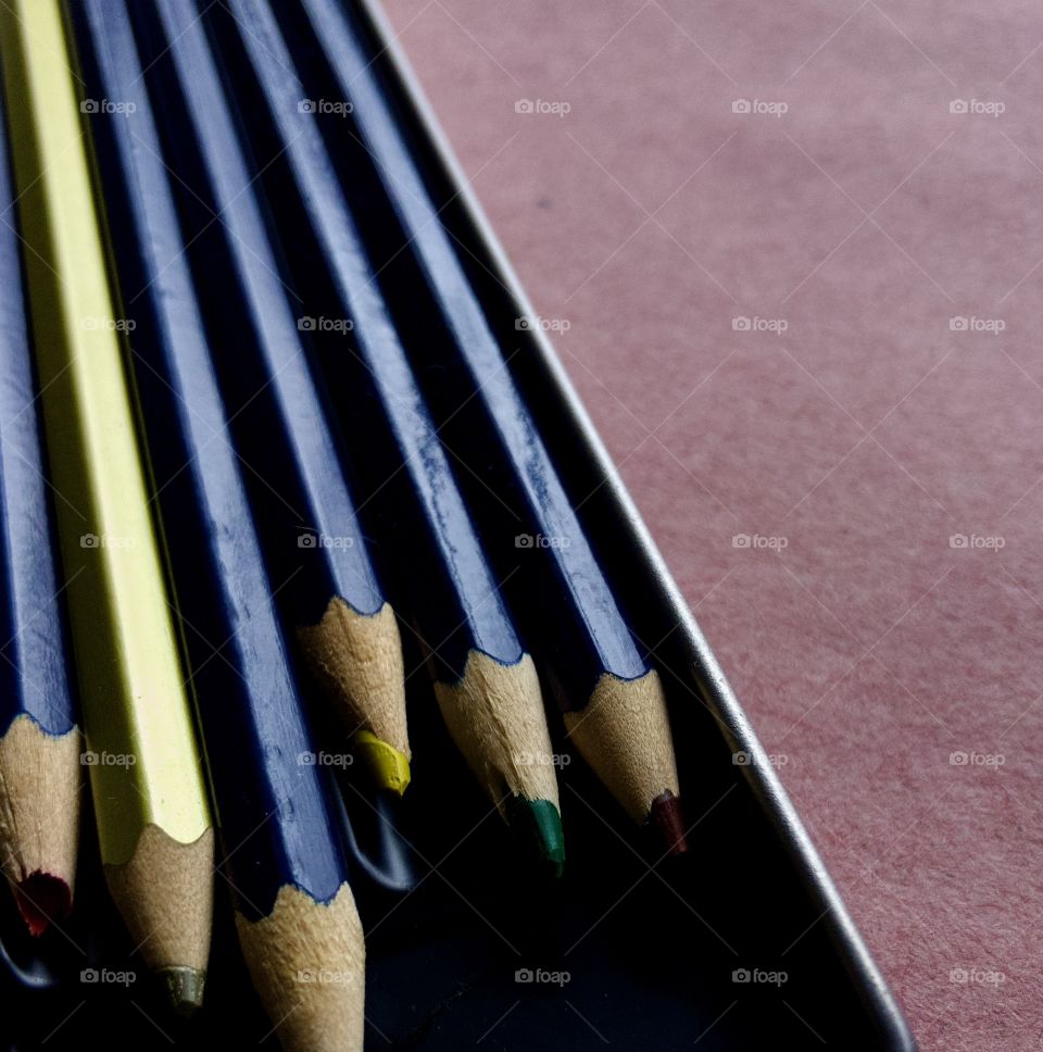 Perspective view of sharpened color pencils in metal tin