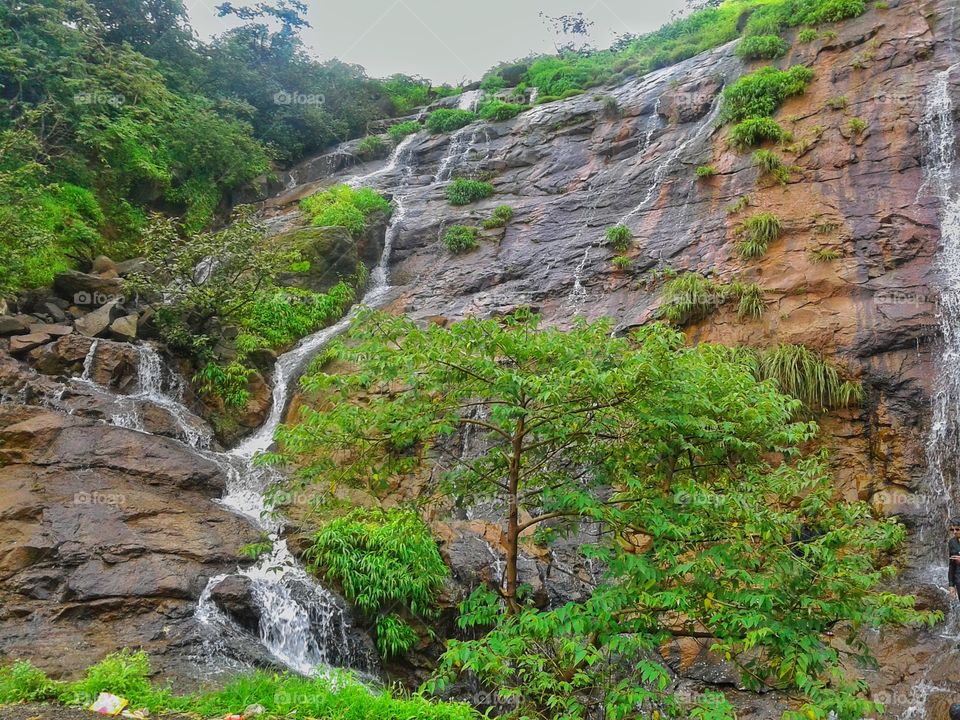 Small waterfall, water is falling down with beautiful surrounding nature.