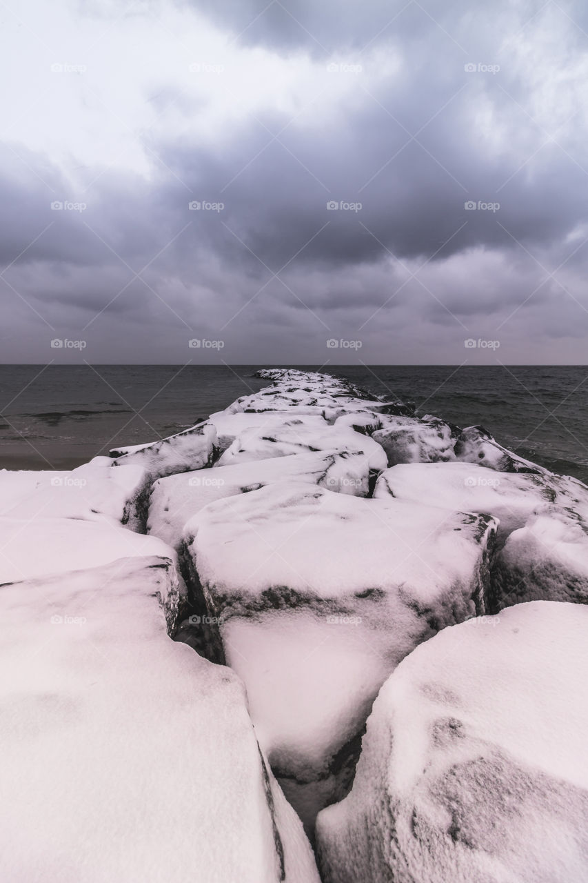 Snow capped jetty on a stormy winter day. 