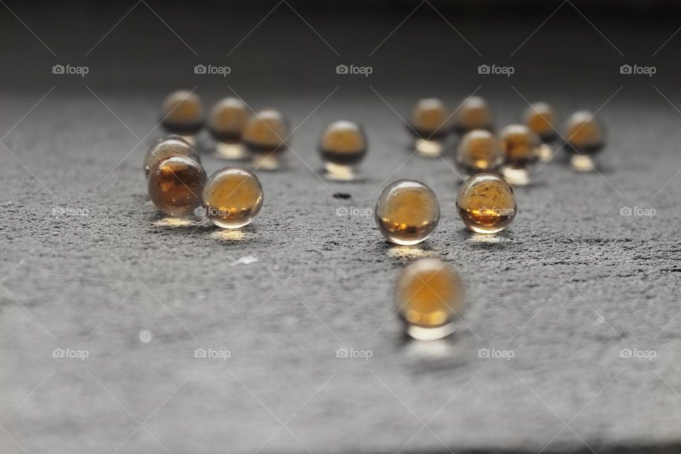 small round balls, almost transparent, are scattered on the concrete floor. fish oil pills.