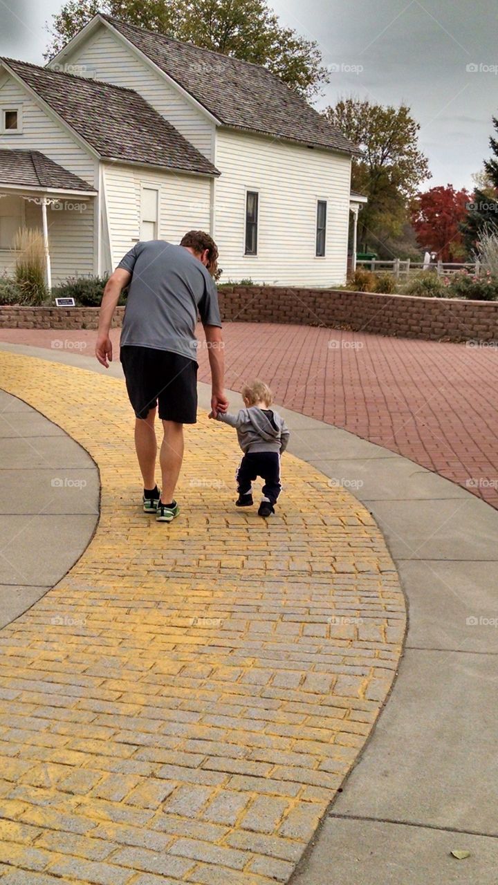Learning to Walk. Father and son at Storybook Land park.  Toddler learning to walk on Yellow Brick Road.