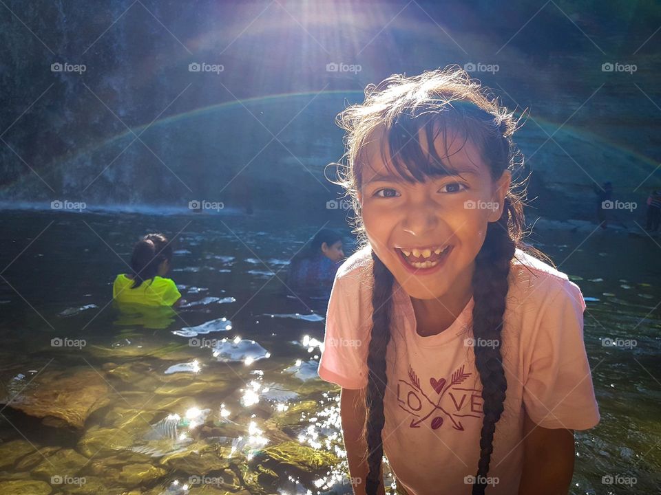 Happy girl is laughing while bathing in a waterfall