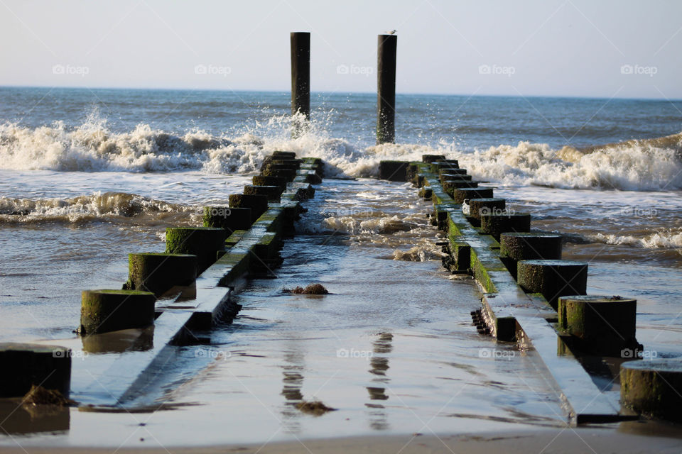 Waves crash into abandoned pier ruins