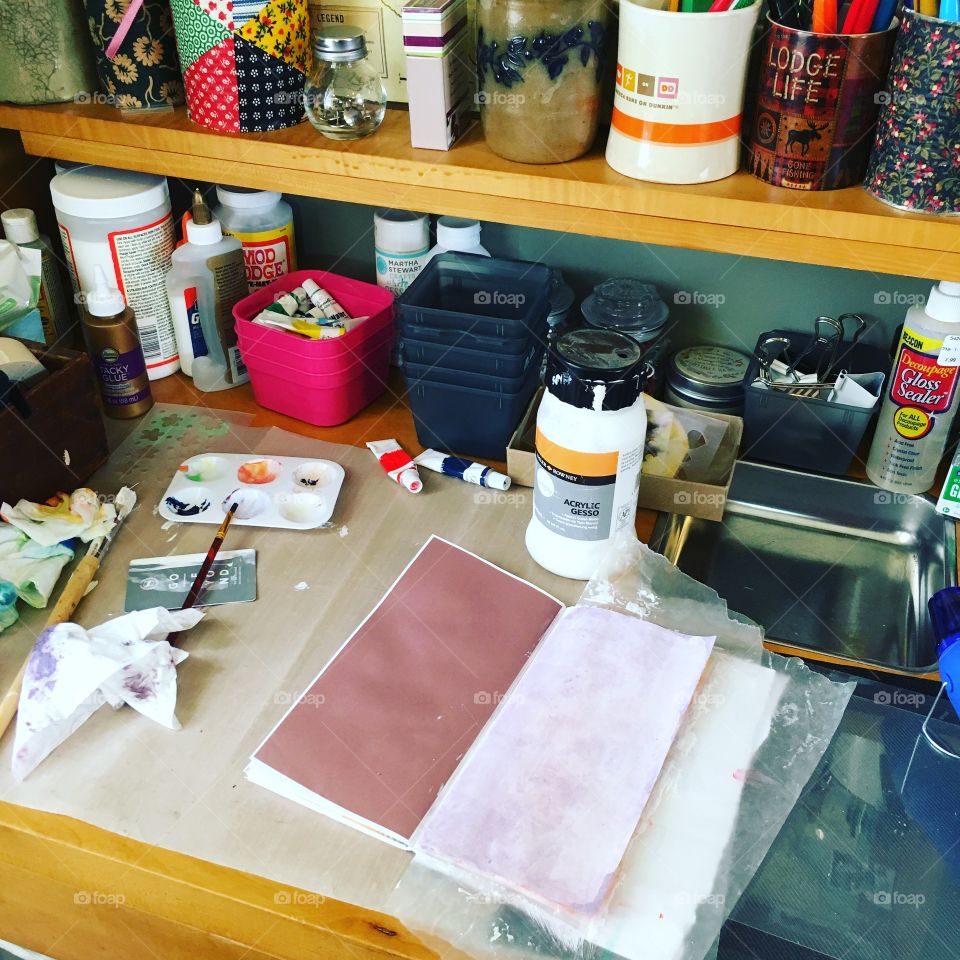 I am prepping the pages in my vacation journal with gesso and paint to coordinate with the corresponding page. I am working in my craft room.