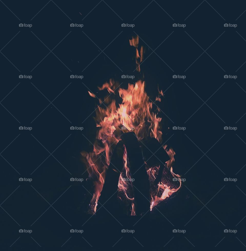 A large, bright, and hot bonfire on the sandy beach large flames