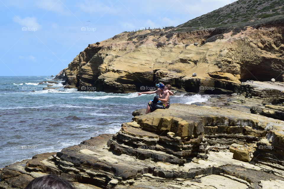 Teenage friends sitting on rock at sea side