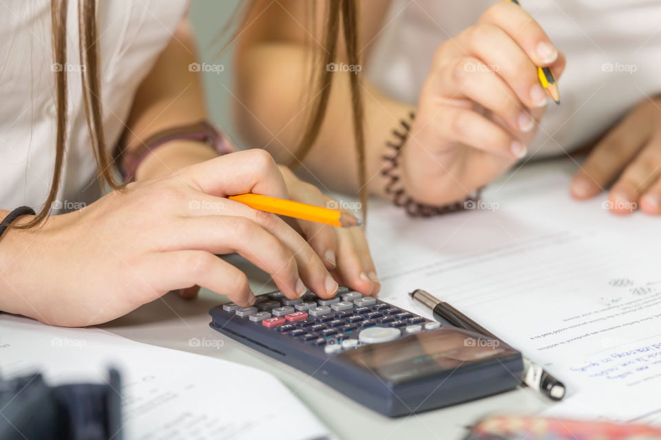 Pupils at the math class using calculator, only hands in frame. Back to school concept.