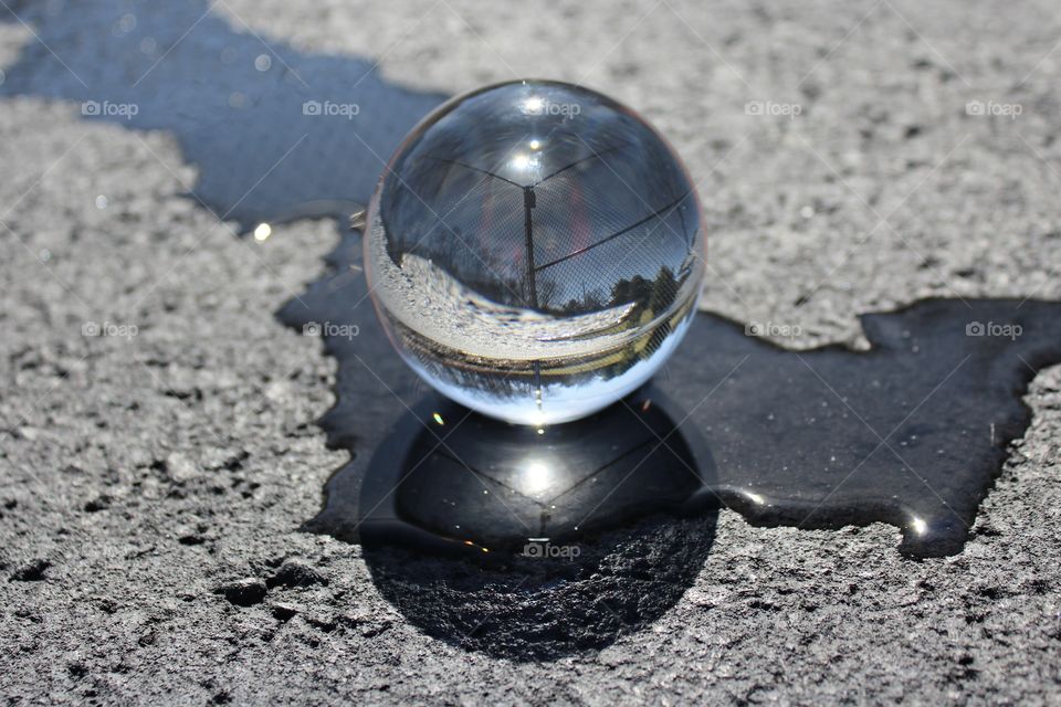 Inverse World; Crystal ball displaying and reflecting a skatepark memory in a stream of water across asphalt.