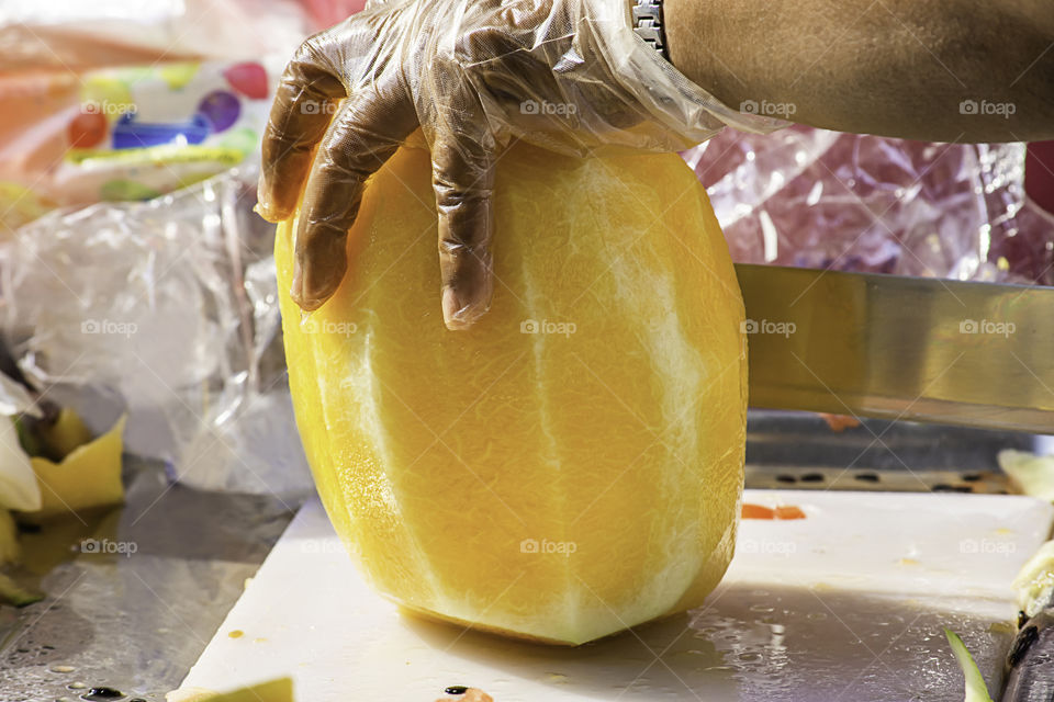 Hand holding yellow watermelon And use a knife to cut a piece.