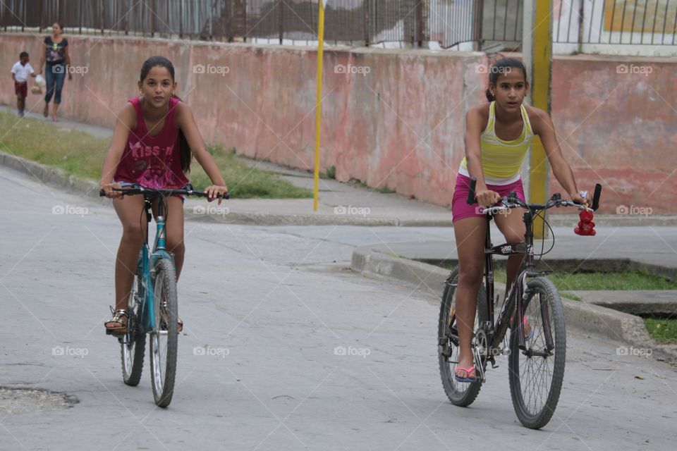 People In Cuba.Youn Girls On Their Bikes