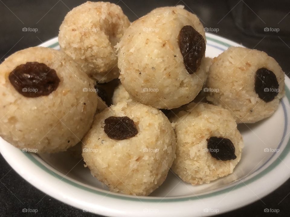 Coconut laddoos - dessert balls made out of finely shredded coconut and condensed milk, with cardamom for additional flavor, topped with raisins 