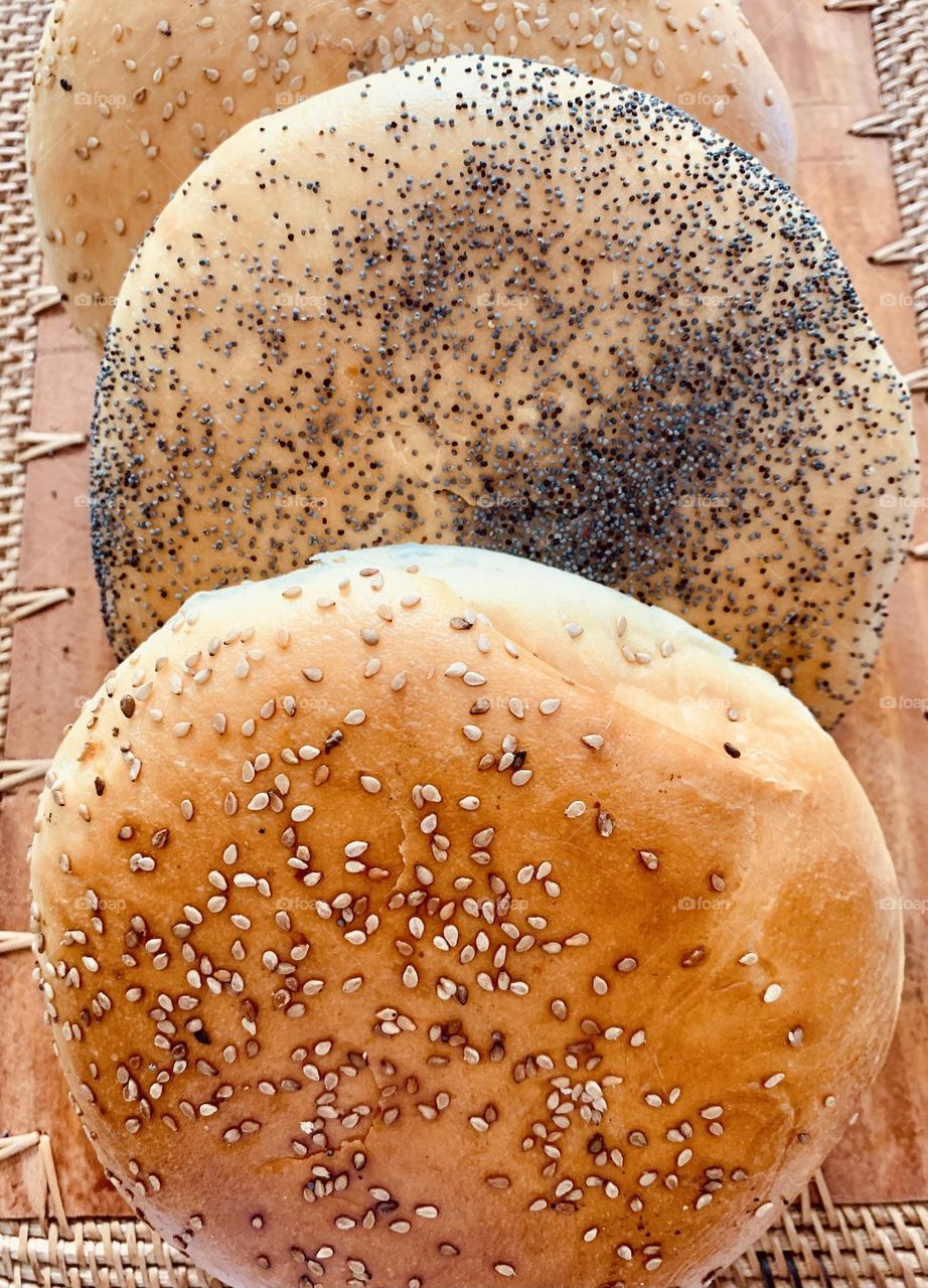 Freshly baked hand made flat golden bread buns covered with sesame and poppy seeds 