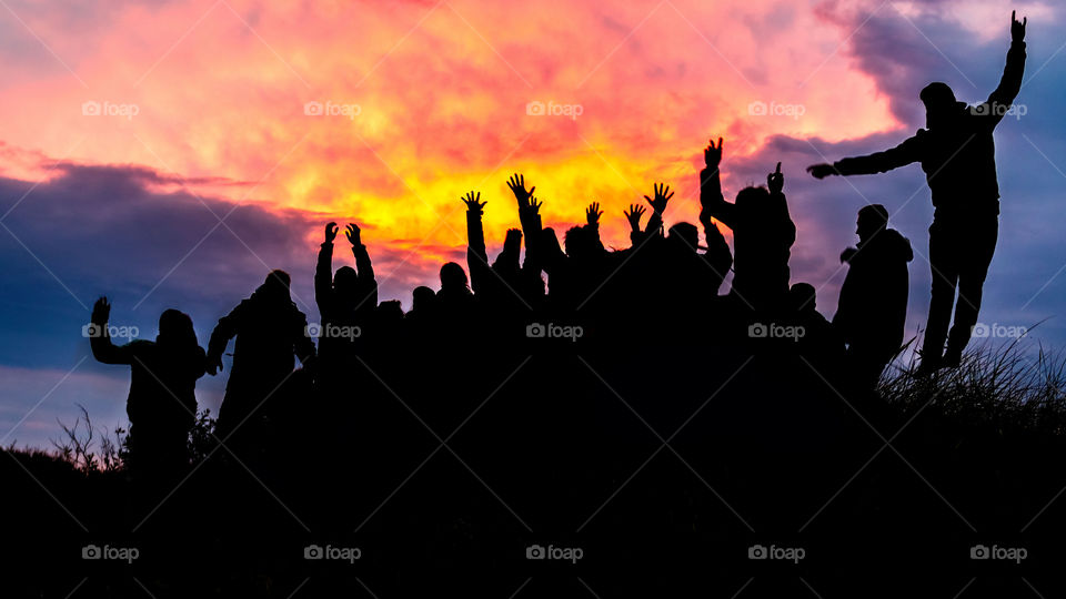 Silhouette, group of happy people jumping in sunset.