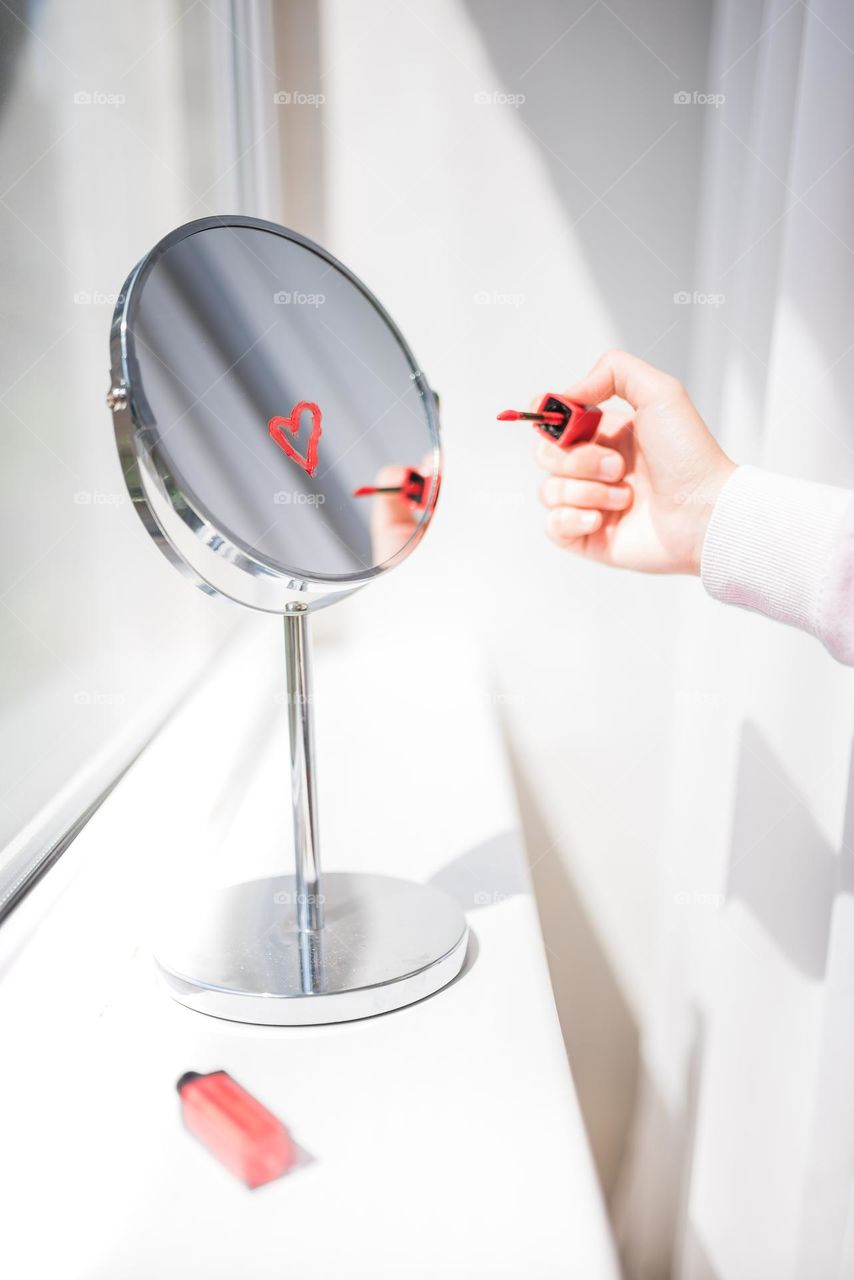 Lipstick heart being drawn on the mirror for self love