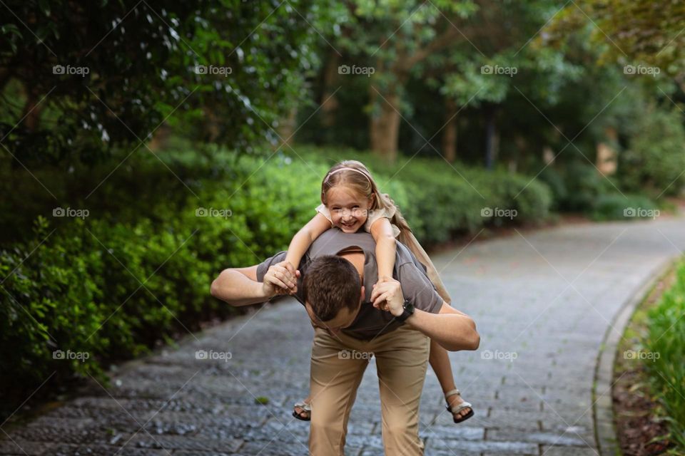 Happy father playing with daughter in park at summer day