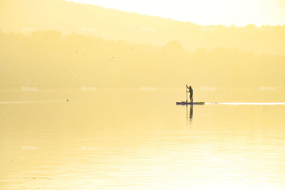 Lonely man rowing in the middle of the lake