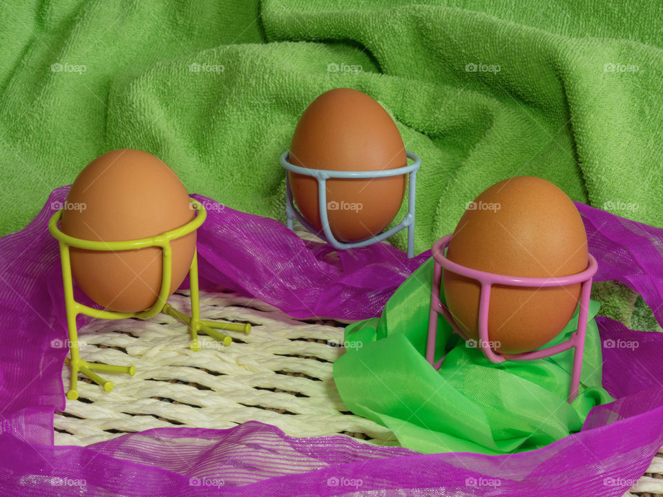 Brown eggs of light color prepare for the holiday Easter against the background from a white rope and dark branches of a tree with bright multi-colored ribbons.
