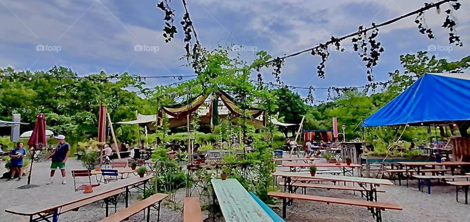 Little „Buddhist“ inspired colorful flags are strung up along a rope across the lake next to the gourmet Asian restaurant in the „English Garden“ of „Munich“, the „Bavarian“ capitol. 2022. Hypnotic Productions