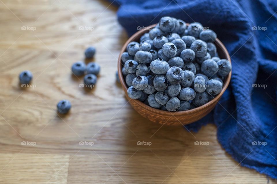 Blueberry in brown bowl on the wooden table, top view 