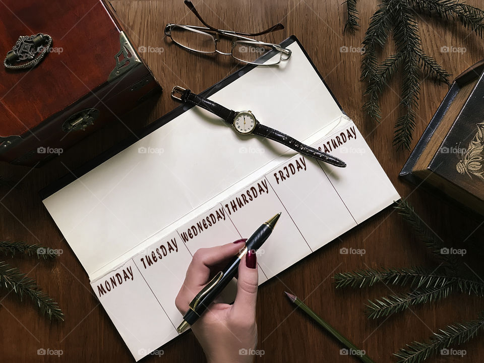 Overheard view of a working space with planning accessories for a week on wooden table 