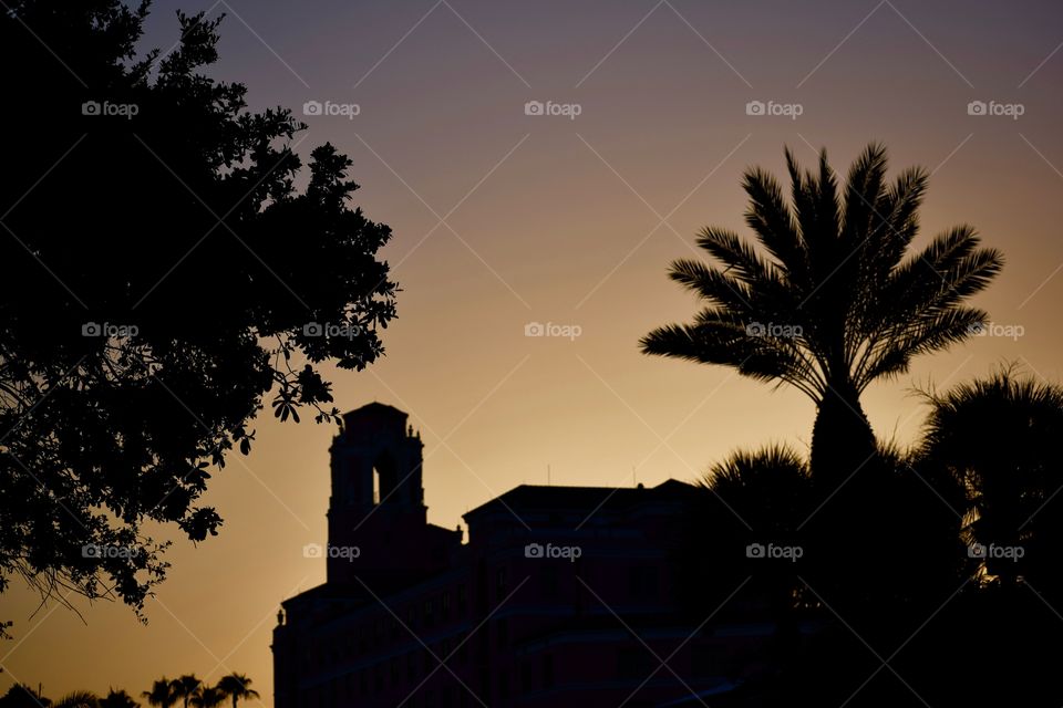 A florida sunset leaves a church building and palm trees in perfect silhouette.