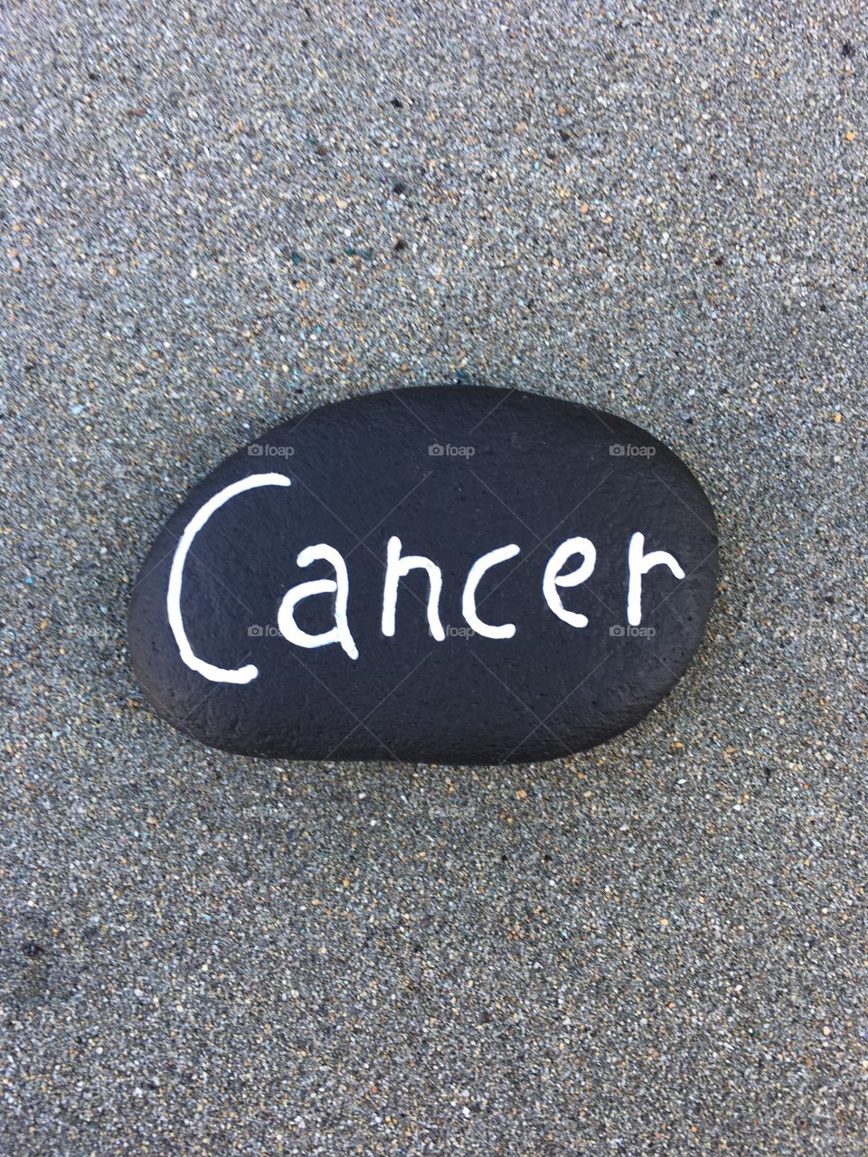 Cancer word carved on a stone over volcano sand 
