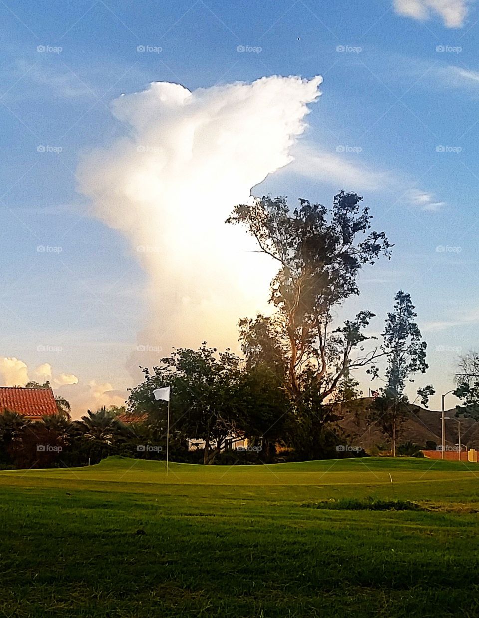 fore. golf course flag with tall cloud backdrop