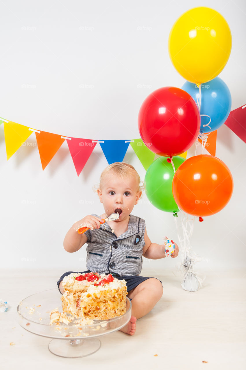 Happy toddler eating his birthday cake. Birthday decorations.