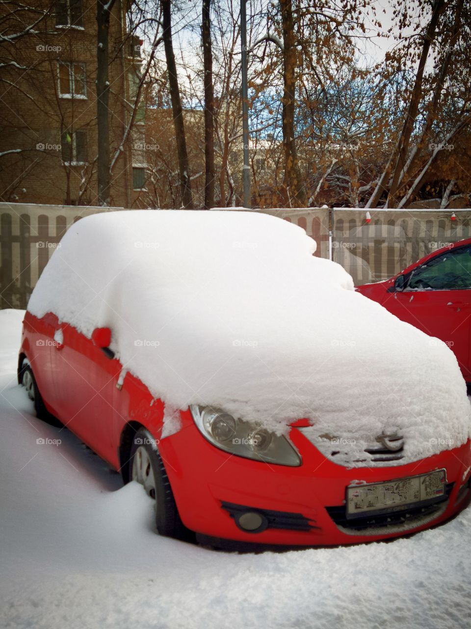 Red car under a thick layer of snow