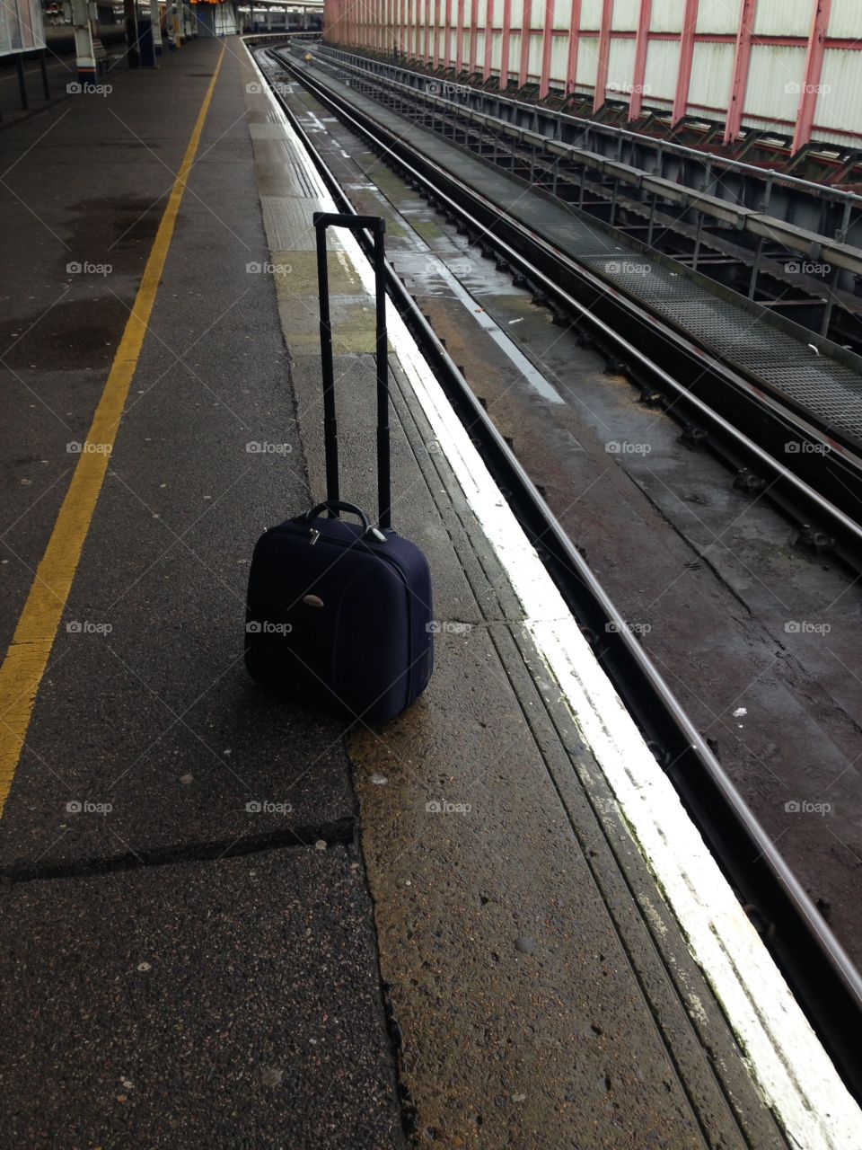 Suitcase on empty train platform 
