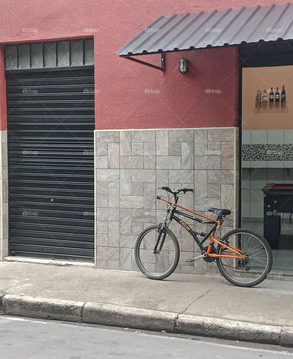 A bycicle left by the entrance of a bar