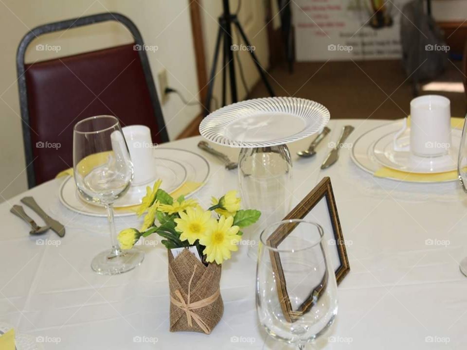 Lovely table accents of a golden picture frame, and gift bag with canary yellow flowers.