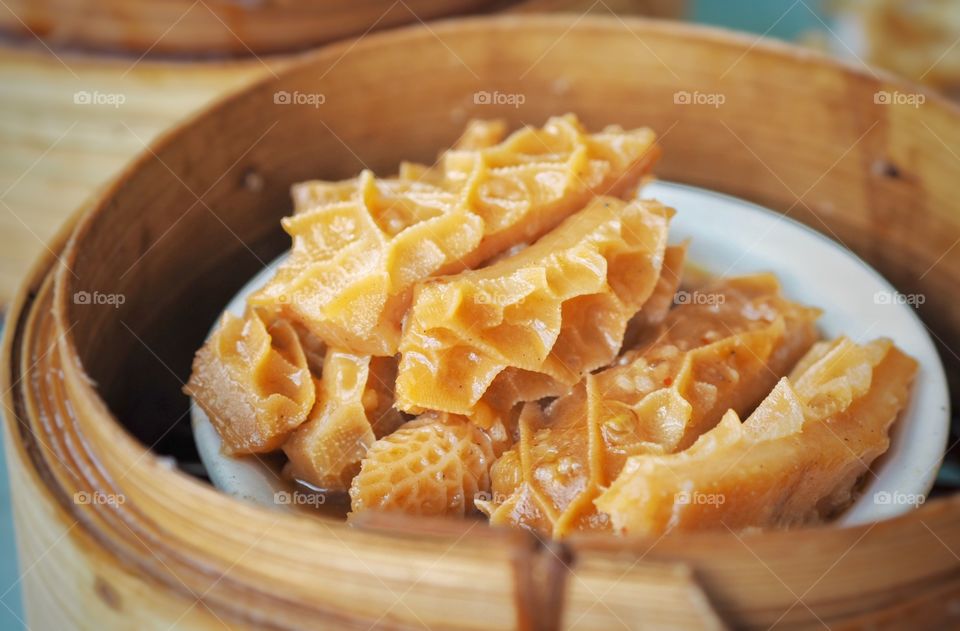 Beef tripe stewed in soy sauce. A popular food item in a yum cha or dim sum line up. It has a firm consistency accompanied by a soft textured mouthfeel. The dish is kept warm inside a bamboo steamer.