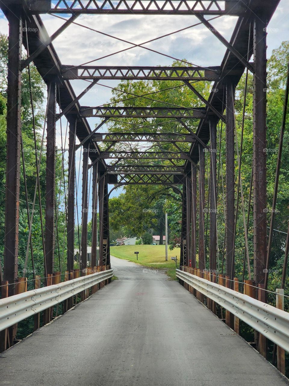 A single lane bridge on a remote backroad in the Midwest United States leads to a small farming community