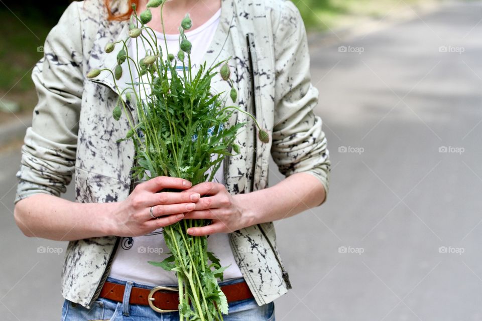 Millennial holding a bouquet of poppy buds 