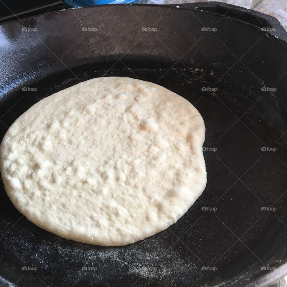 Pita dough getting hot and bubbly on the burning cast iron skillet. Freshly made from scratch to be enjoyed while still warm. 