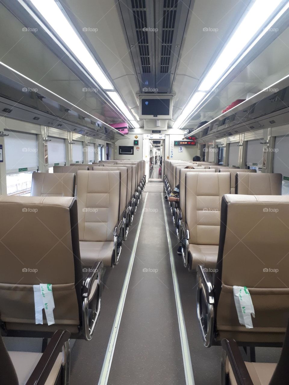brown chairs lined up on a train equipped with plastic bags behind the seats